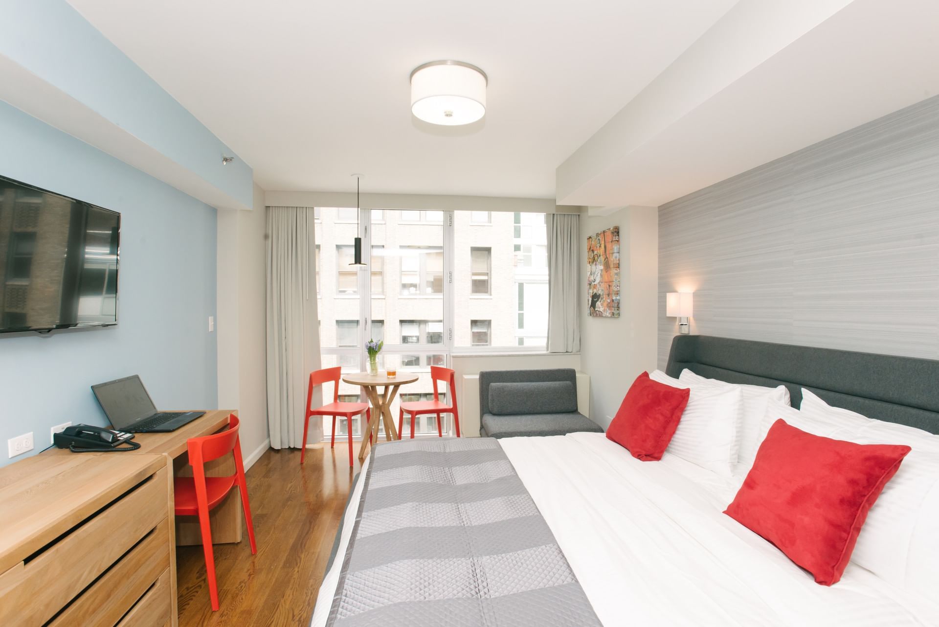 A wide view of a hotel room with a king-sized bed, desk, sofa bed, and dining table.