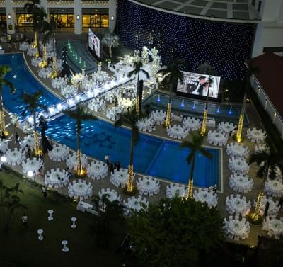 Aerial view of an elegant outdoor night event with white tables arranged around a pool at Hanoi Daewoo Hotel