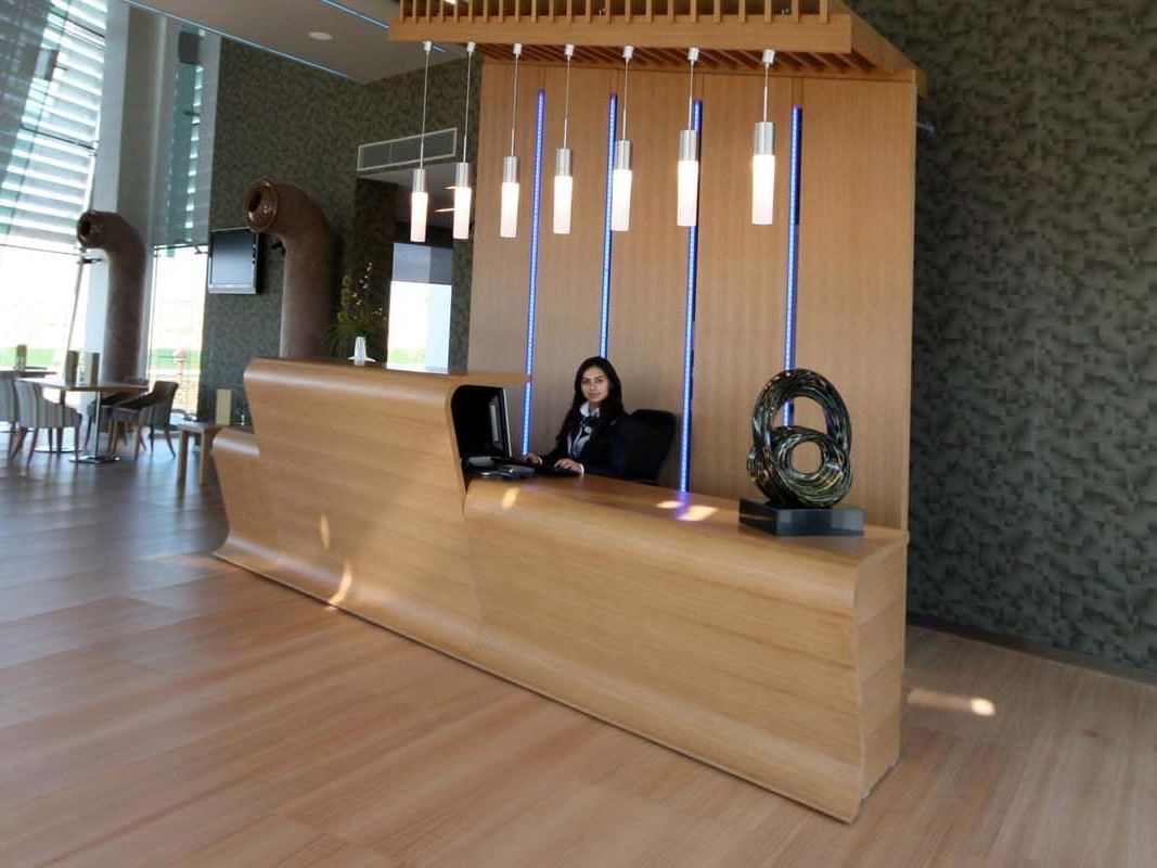Spacious lobby with wooden reception table & hanging lights at Titanic Anadolu Gebze