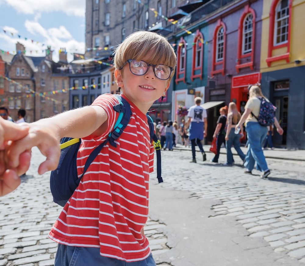 Young boy holding a hand by a cobblestone street near The Capital Hotel, Apartments and Townhouse