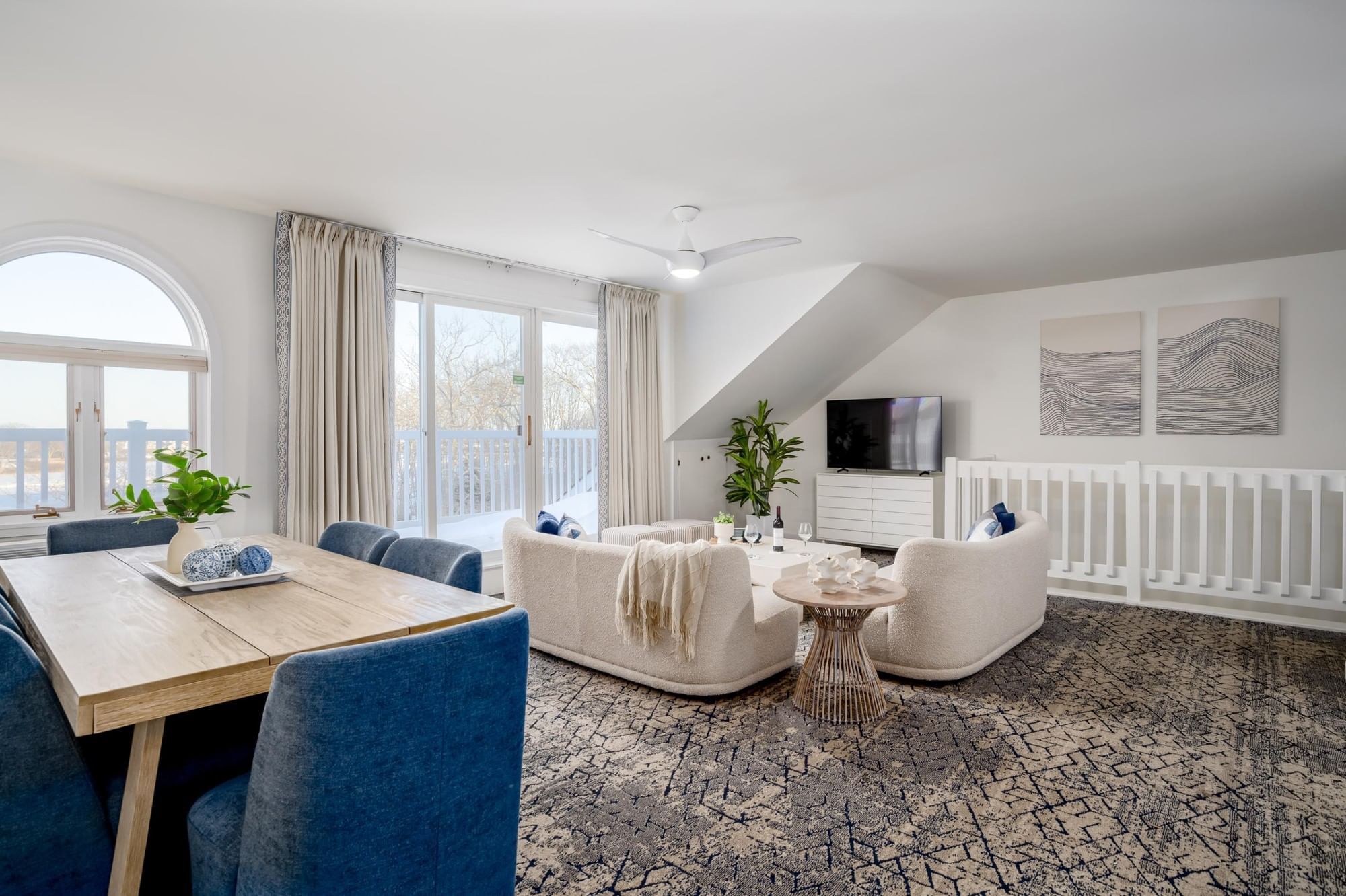 A wide view of a penthouse suite with a dining area, living area, and balcony access.