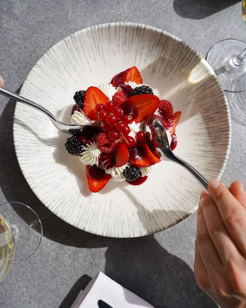 Dessert aux fruits rouges avec chantilly et coulis servi dans une assiette texturée au Warwick Reine Astrid-Lyon