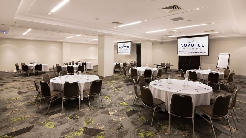 Protea Conference Room set with banquet tables facing a projector screen at Novotel Sydney International Airport