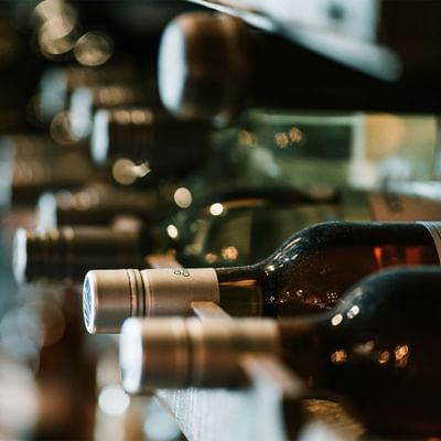 Close-up of elegant wine bottles with glossy labels in a wooden rack at the Falkensteiner Hotel Schladming