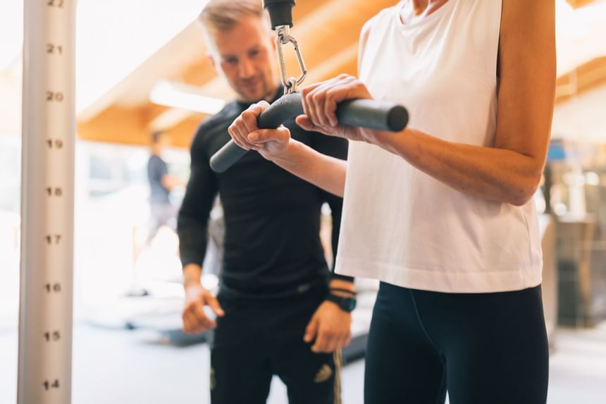 Personal fitness trainer helping a lady at a gym in Liebes Rot