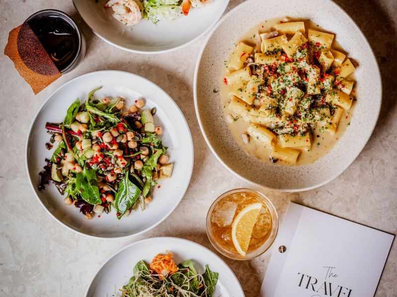 Four plates of assorted dishes with a by day menu from The May Fair Bar