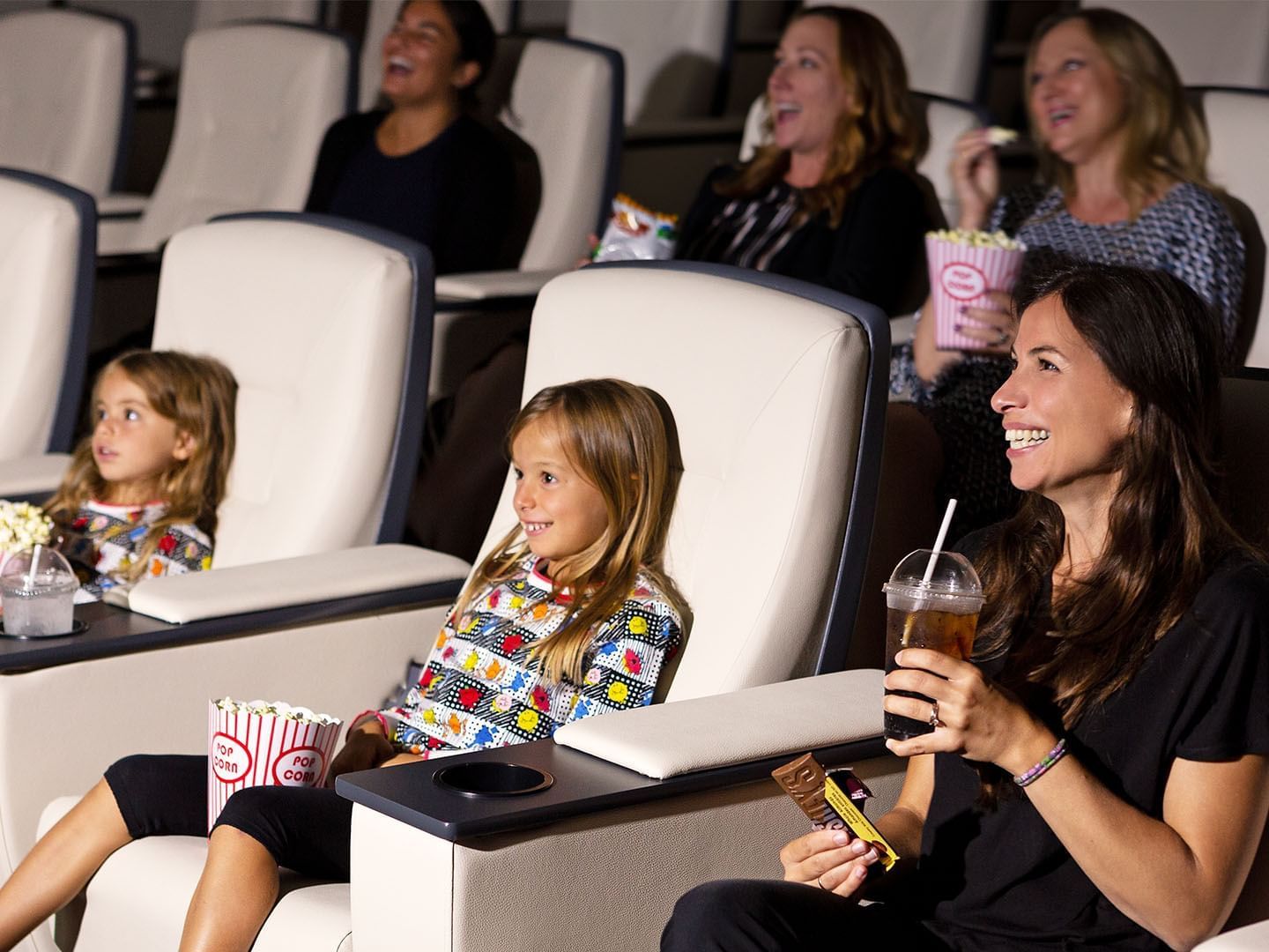Audience with snacks and drinks enjoying a movie in the Screening Room at Hotel X Toronto, a hotel Downtown Toronto