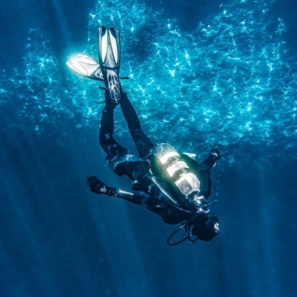 Diver diving in the deep sea near Falkensteiner Hotels