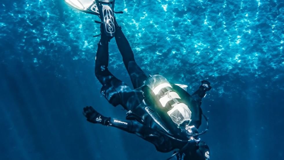 Diver diving in the deep sea near Falkensteiner Hotels