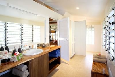 Bathroom with dual vanity, towels, and shuttered windows in Beachfront Bures at Musket Cove Island Resort & Marina