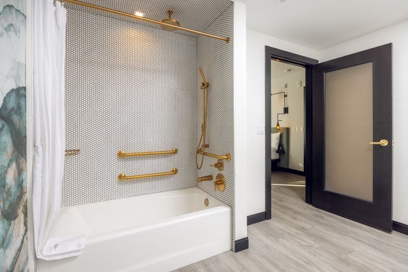 A bathroom with a white bathtub and gold shower fixtures.
