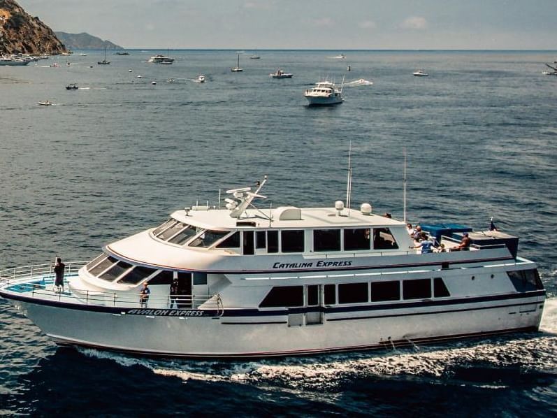 Close-up view of a yacht cruising on the sea with other boats in the background near Banning House Lodge