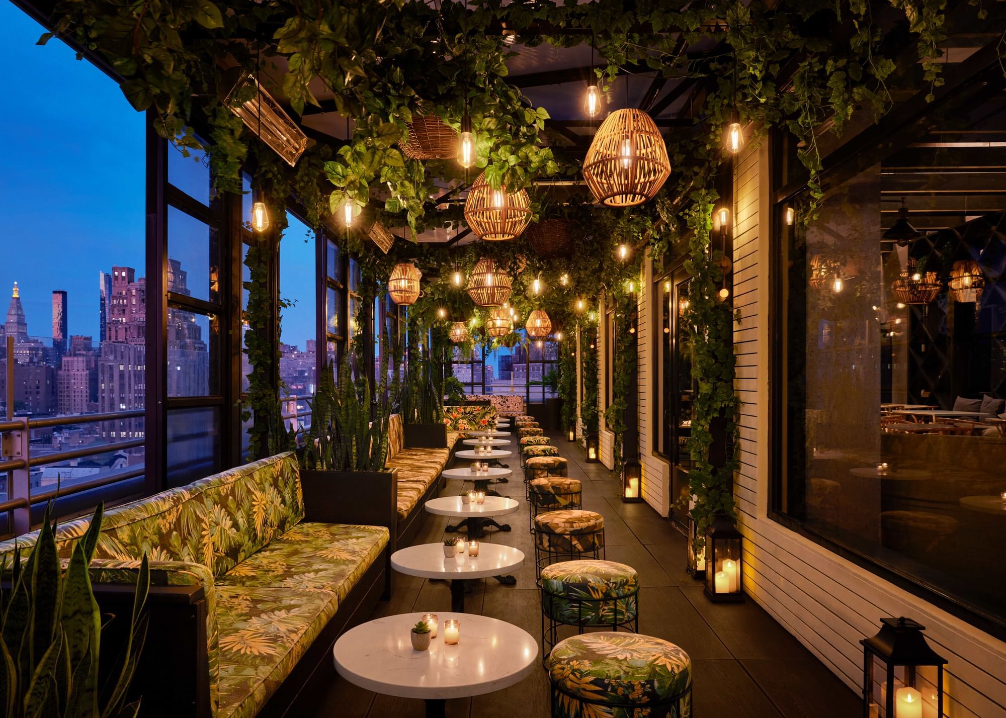 Outdoor seating at Gansevoort Rooftop with the Manhattan skyline in the background at night