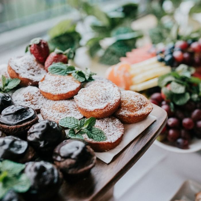 Assorted desserts with berries and mint on a wooden tray at Mercure Charlestown.