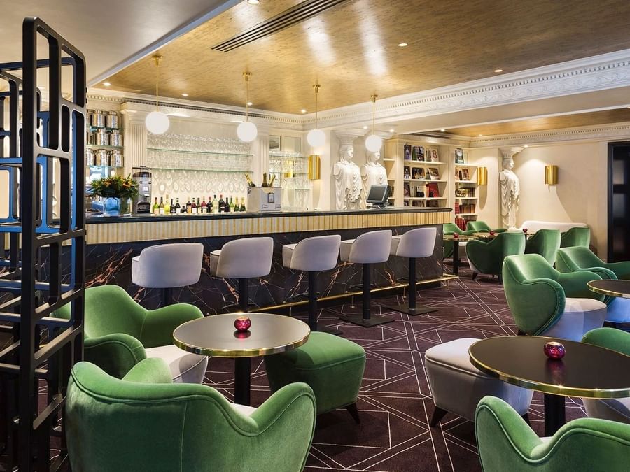 Stylish marble bar with green velvet seating and classic statues at Hotel Barsey by Warwick