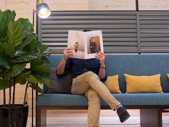 A man reading a magazine on a sofa in lobby of Park Hotel Group