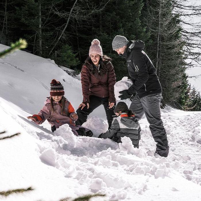 A family playing with snow near Falkensteiner Hotel Montafon