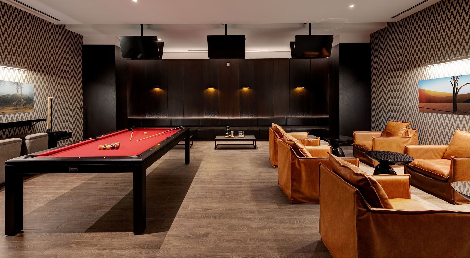 Bow Tie Room with a red pool table, tan sofas, chevron walls, and art décor at Hotel X Toronto