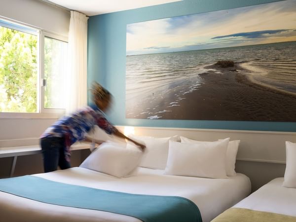 A lady arranging a bed in a room at Hôtel de l'Europe