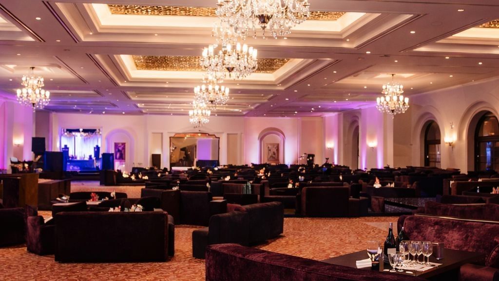 Expansive lounge area with velvet seating under large crystal chandeliers at Serena Hotels & Resorts