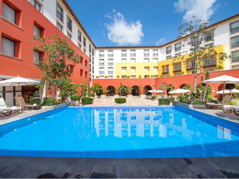 Outdoor pool area with sun loungers and patio umbrellas at Grand Fiesta Americana Querétaro