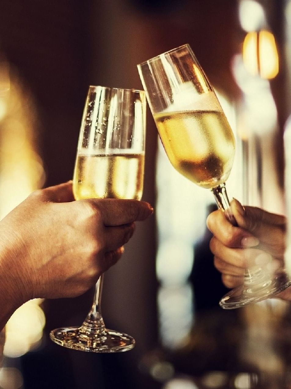 Deux femmes trinquent avec du vin mousseux dans d'élégantes flûtes au Warwick Hotels & Resorts.