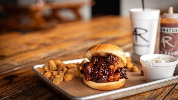 A metal sheet tray with fried okra, a bun with vegan burnt ends, and a drink cup with the 4Rivers logo. 