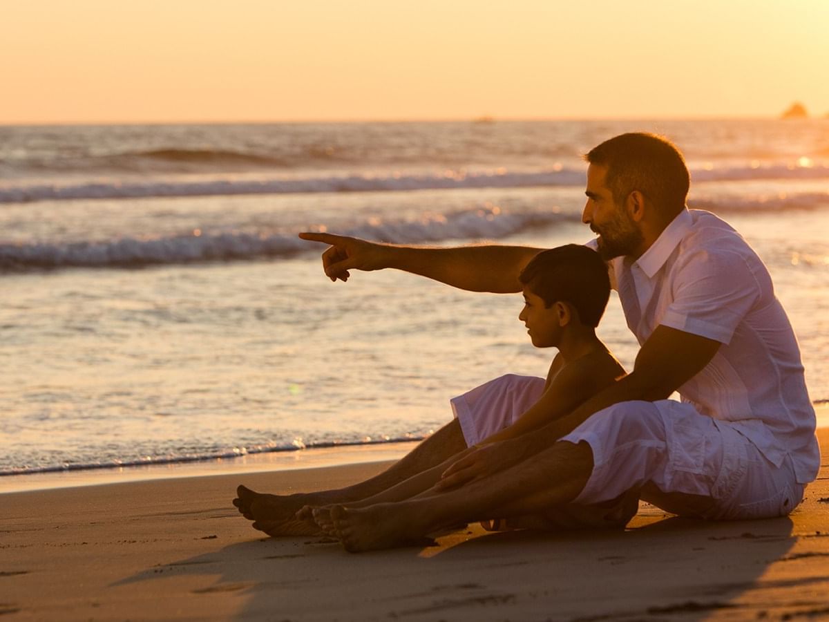 Father & son sitting on the beach at Pierre Mundo Imperial