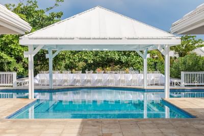 Banquet table under a white pavilion by the pool at Roatan wedding venues Barefoot Cay Resort & Marina
