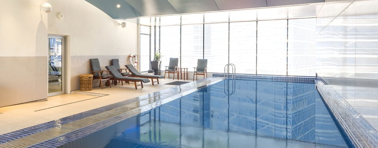 Indoor pool area with loungers at Novotel Sydney Darling Square