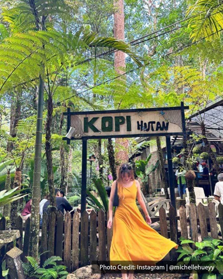 A lady was taking a picture in front of the Kopi Hutan's signboard - Lexis Suites Penang