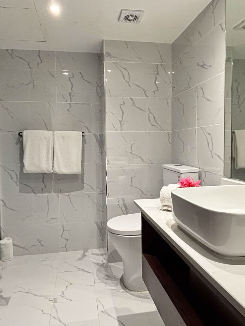 Square vessel sink by a walk-in shower featuring teal subway tiles and marble walls at Warwick Hotels & Resorts