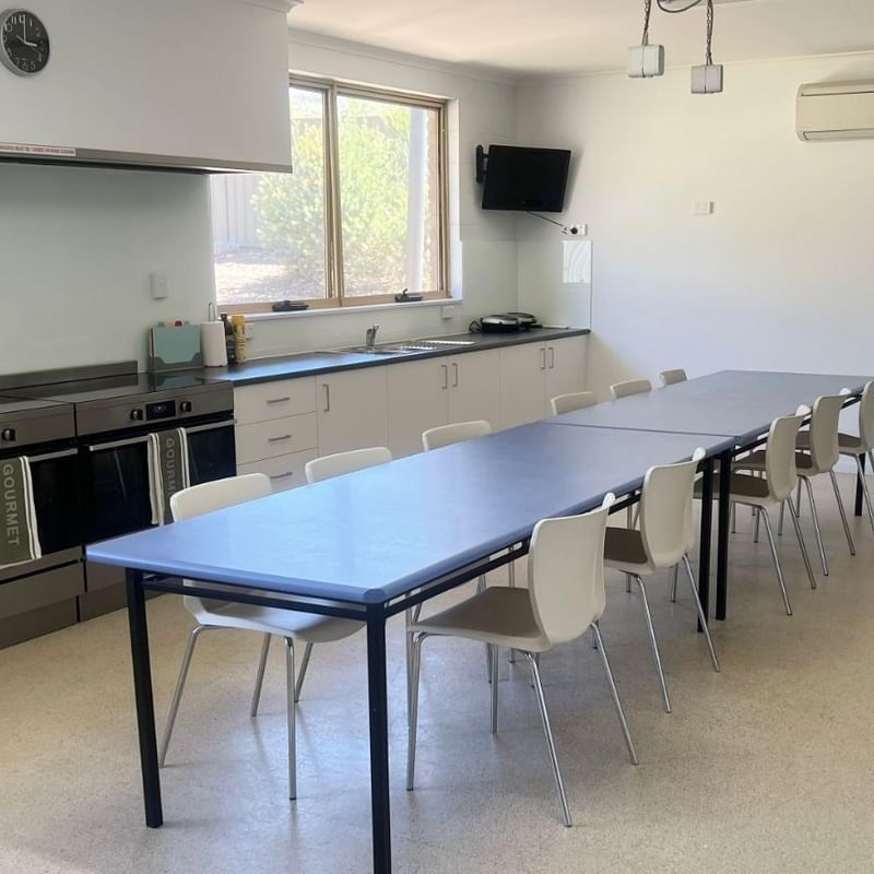White kitchen with large ovens, dining area, and windows at La Trobe University - Orde House.