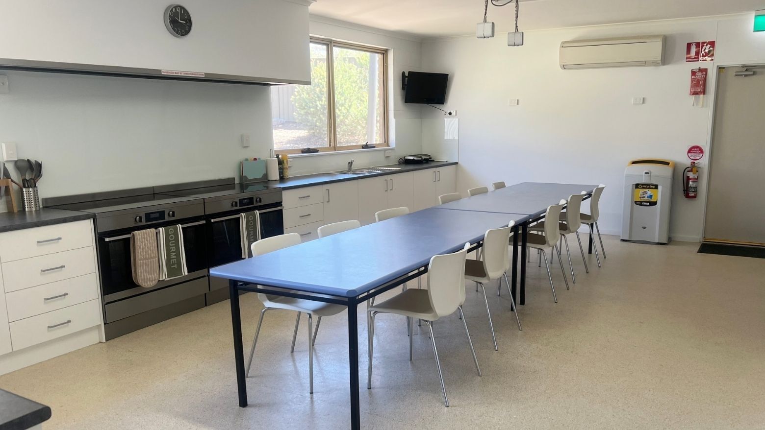 White kitchen with large ovens, dining area, and windows at La Trobe University - Orde House.