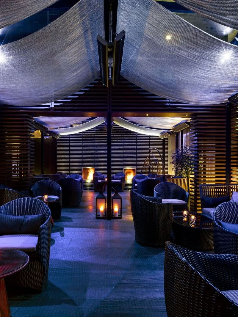 Elegant lounge with wicker chairs, candles, and drapes at The May Fair Hotel, London.