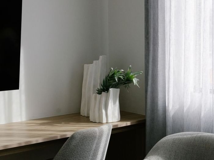 Sunset Junior Suite at Elysium Manly with white sculptural vases & greenery by a wooden desk under sheer curtains & a chair