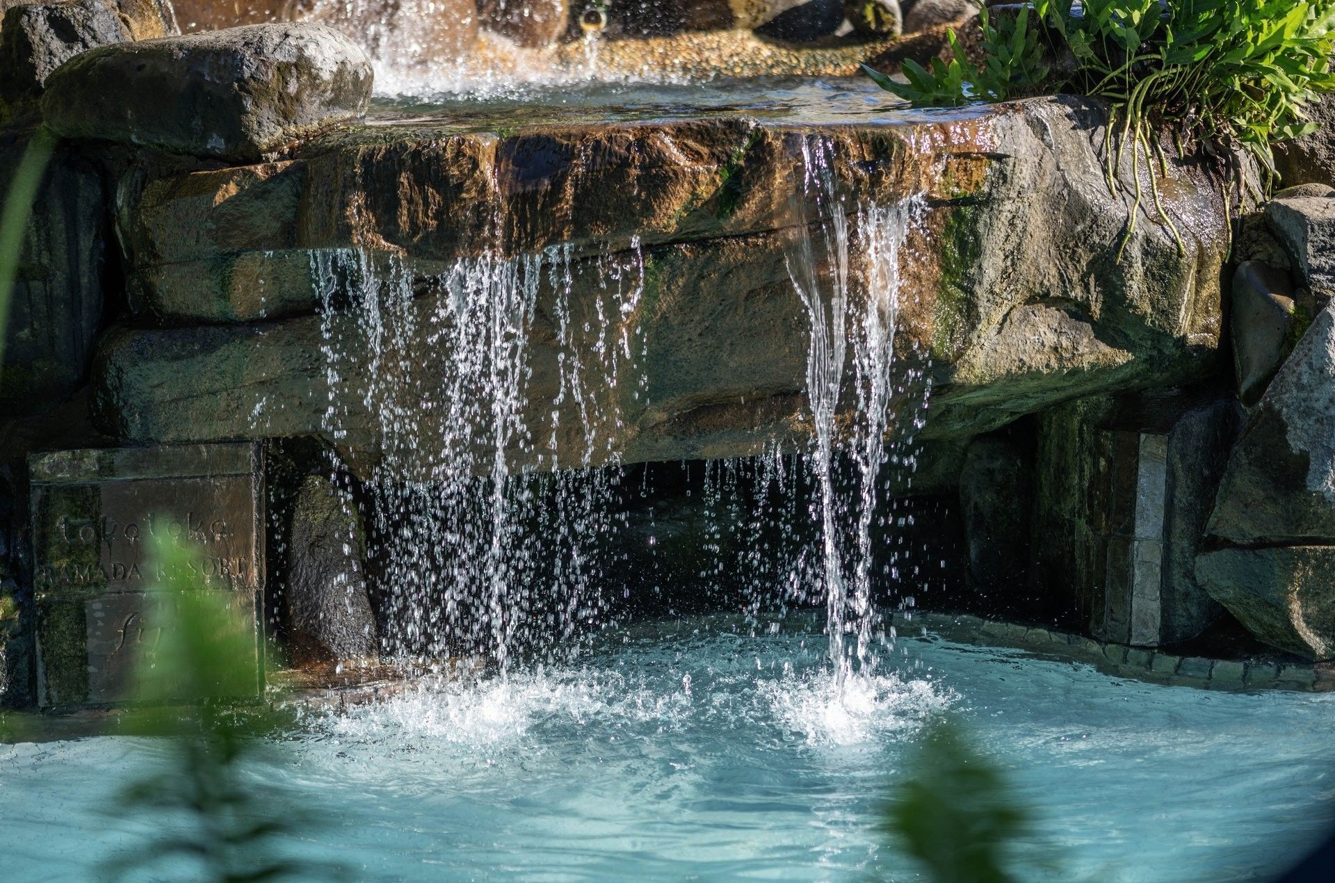 Water cascading from a stone ledge into a bright blue Swimming pool at TokaToka Resort Nadi Fiji