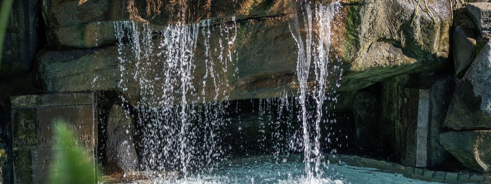 Water cascading from a stone ledge into a bright blue Swimming pool at TokaToka Resort Nadi Fiji