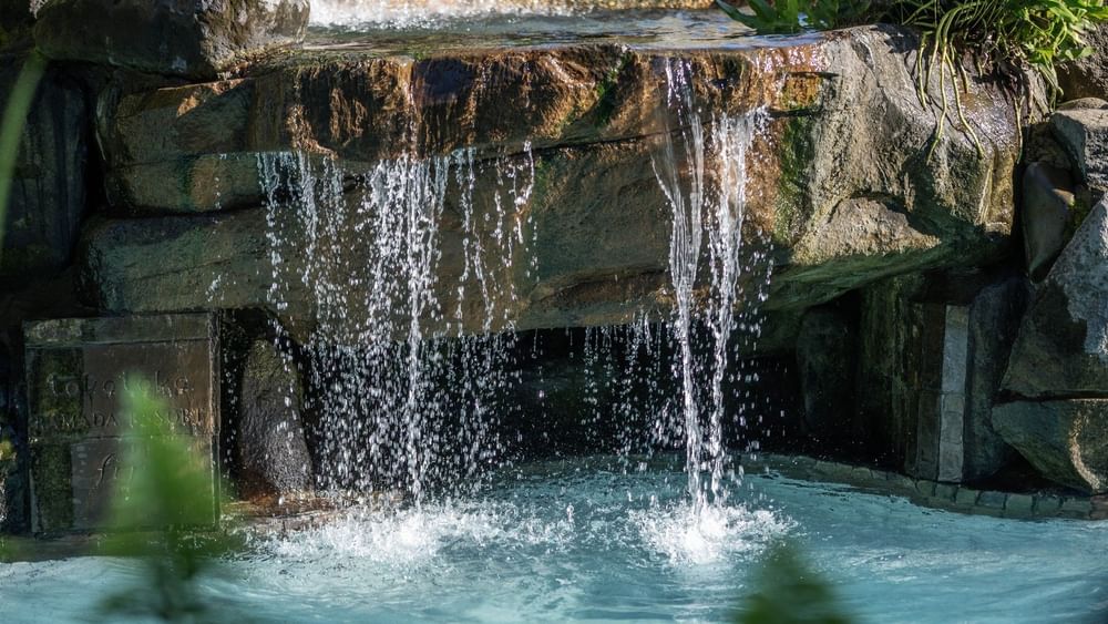 Water cascading from a stone ledge into a bright blue Swimming pool at TokaToka Resort Nadi Fiji