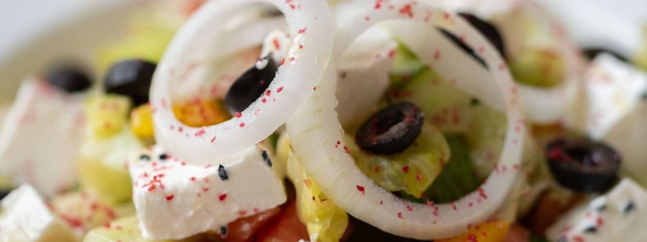 Close-up of a fresh salad featuring diced cucumber, onion rings, & feta cheese in Seasons Restaurant at Warwick Hotel Jeddah