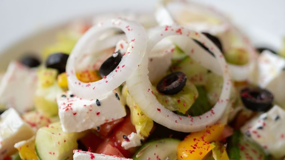 Close-up of a fresh salad featuring diced cucumber, onion rings, & feta cheese in Seasons Restaurant at Warwick Hotel Jeddah