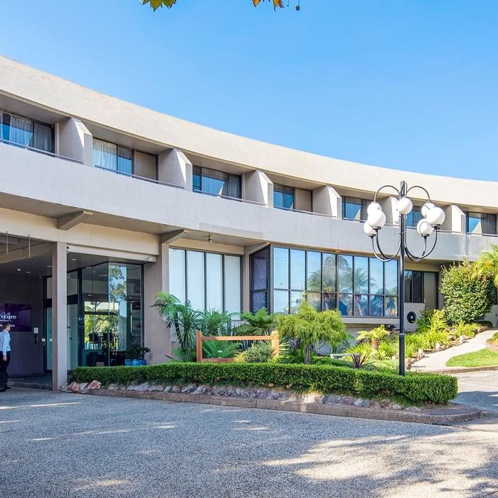Exterior view of the hotel entrance with a lush greenery lawn at Mercure Charlestown