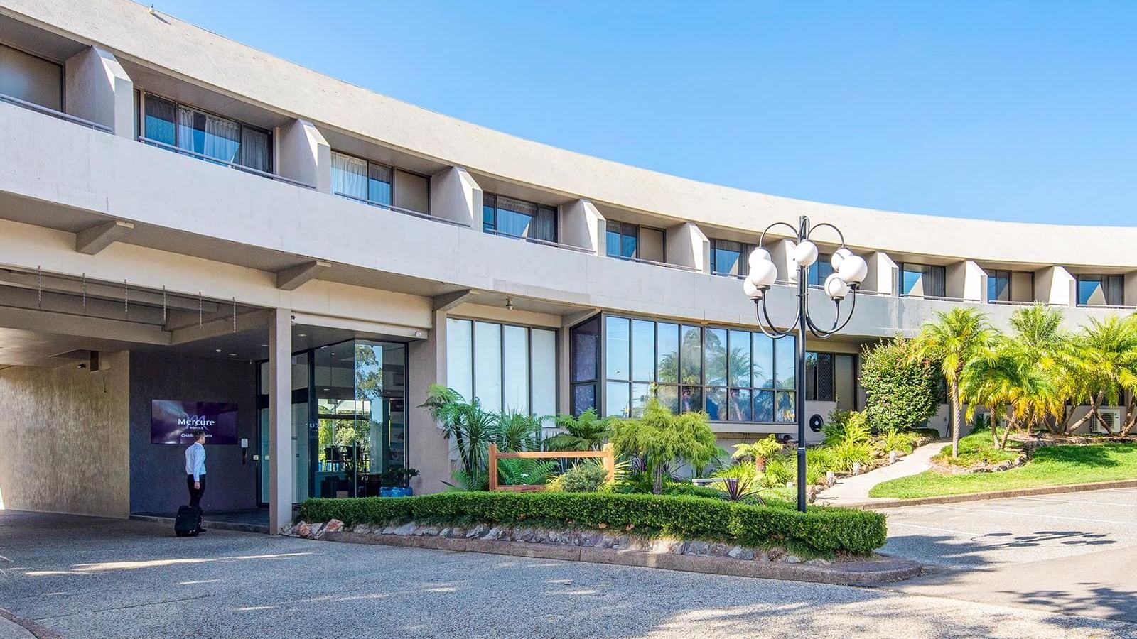 Exterior view of the hotel entrance with a lush greenery lawn at Mercure Charlestown