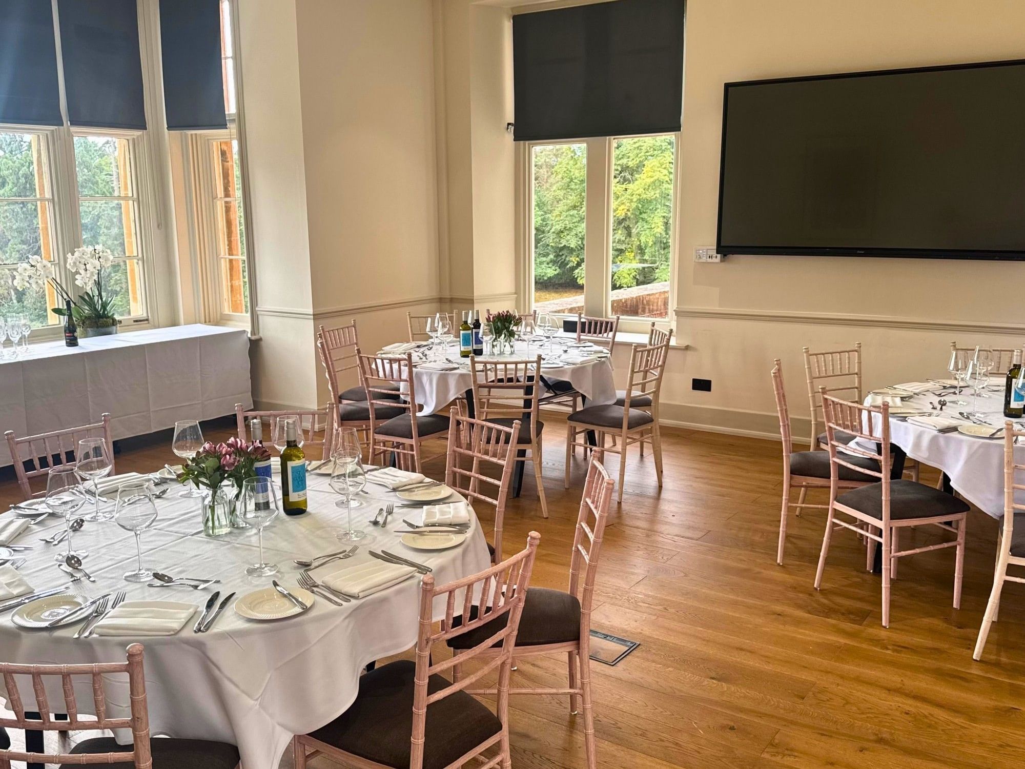 Pope event room with elegant dining tables, rose gold chairs and garden views at Easthampstead Park Hotel, Bracknell