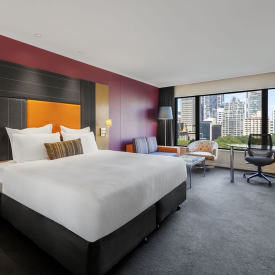 Workspace and lounge area by the bed in Classic Room with carpeted floors at Pullman Sydney Hyde Park