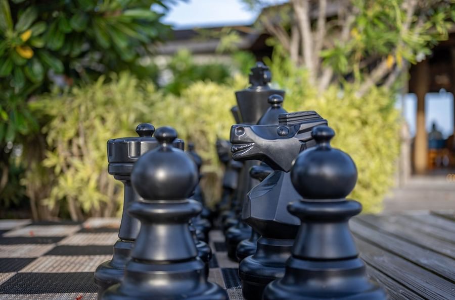Large black chess pieces on a checkered board surrounding lush green bushes at Warwick Paradise Island Bahamas