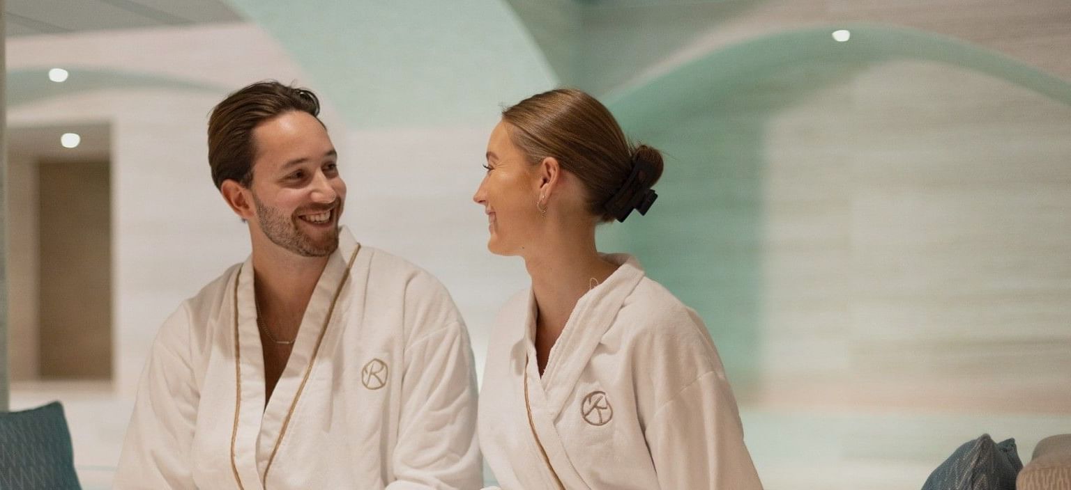 Couple in bathrobes sitting on a couch at Hotel Riverton