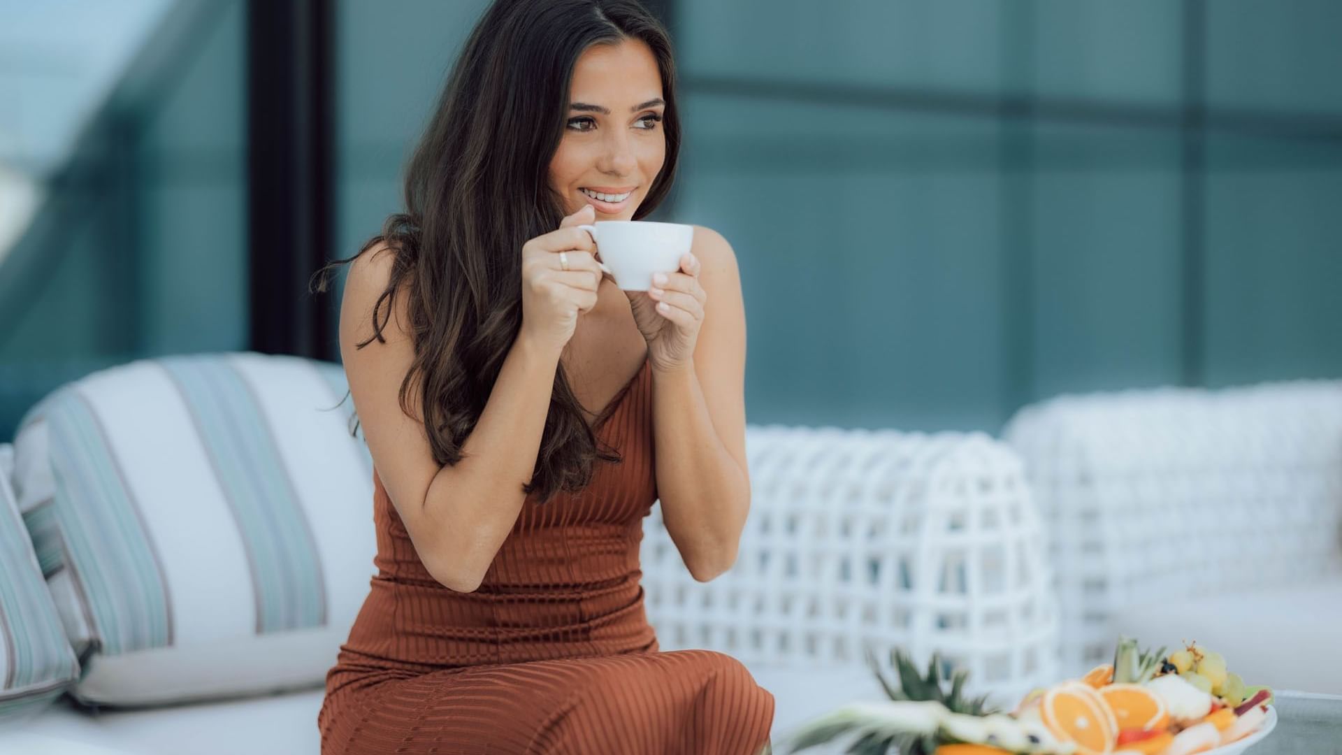 A woman in a dress enjoying a cup of coffee at DAMAC Maison Distinction