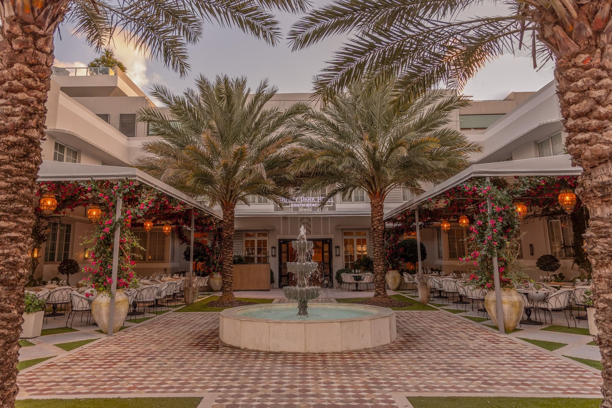 A courtyard with a fountain, palm trees, and outdoor seating area