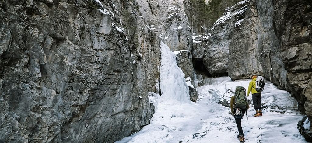 Hikers admire a frozen waterfall on a hike near Banff.